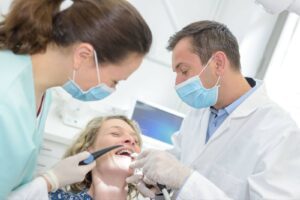 Dentist and assistant examining a smiling patient in a dental clinic